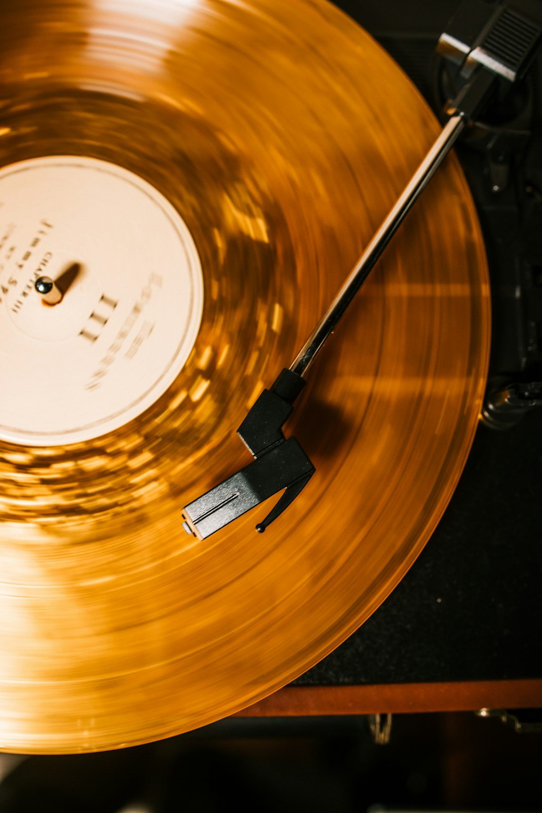 Springfield Packing: Vinyl Records and Turntable Parts 17 Amber vinyl record playing beneath a black turntable tonearm
