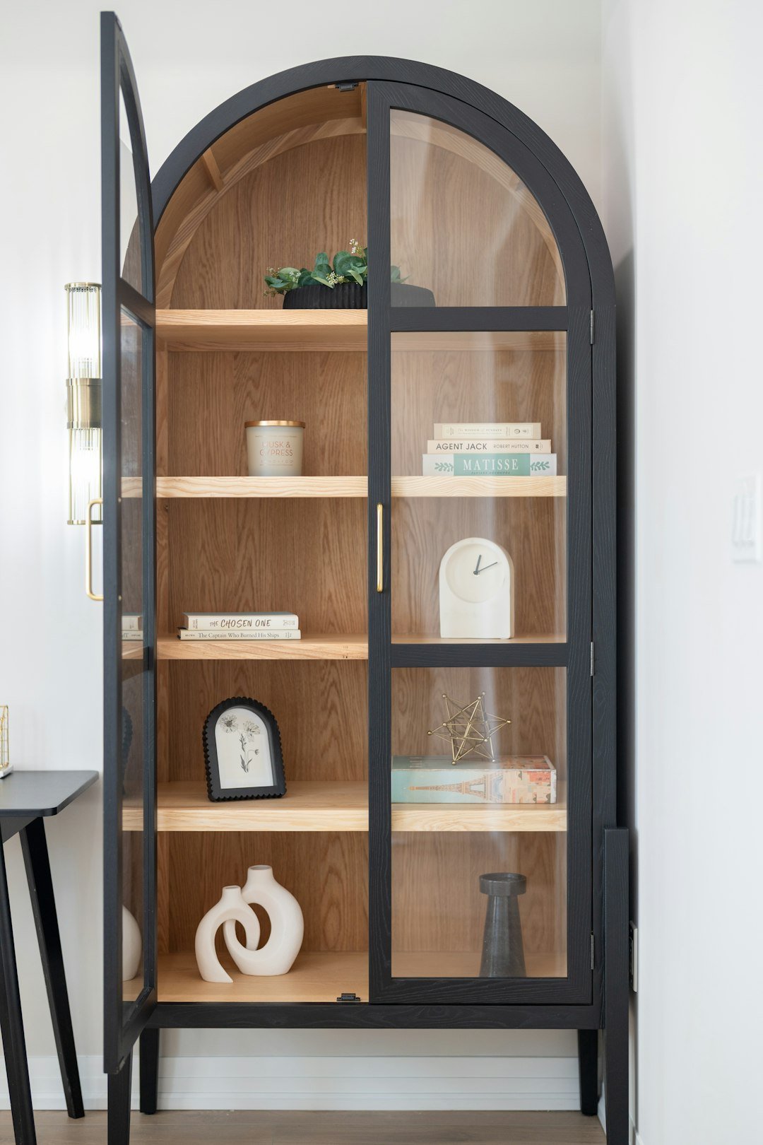 Arched display cabinet with glass doors and decorative objects